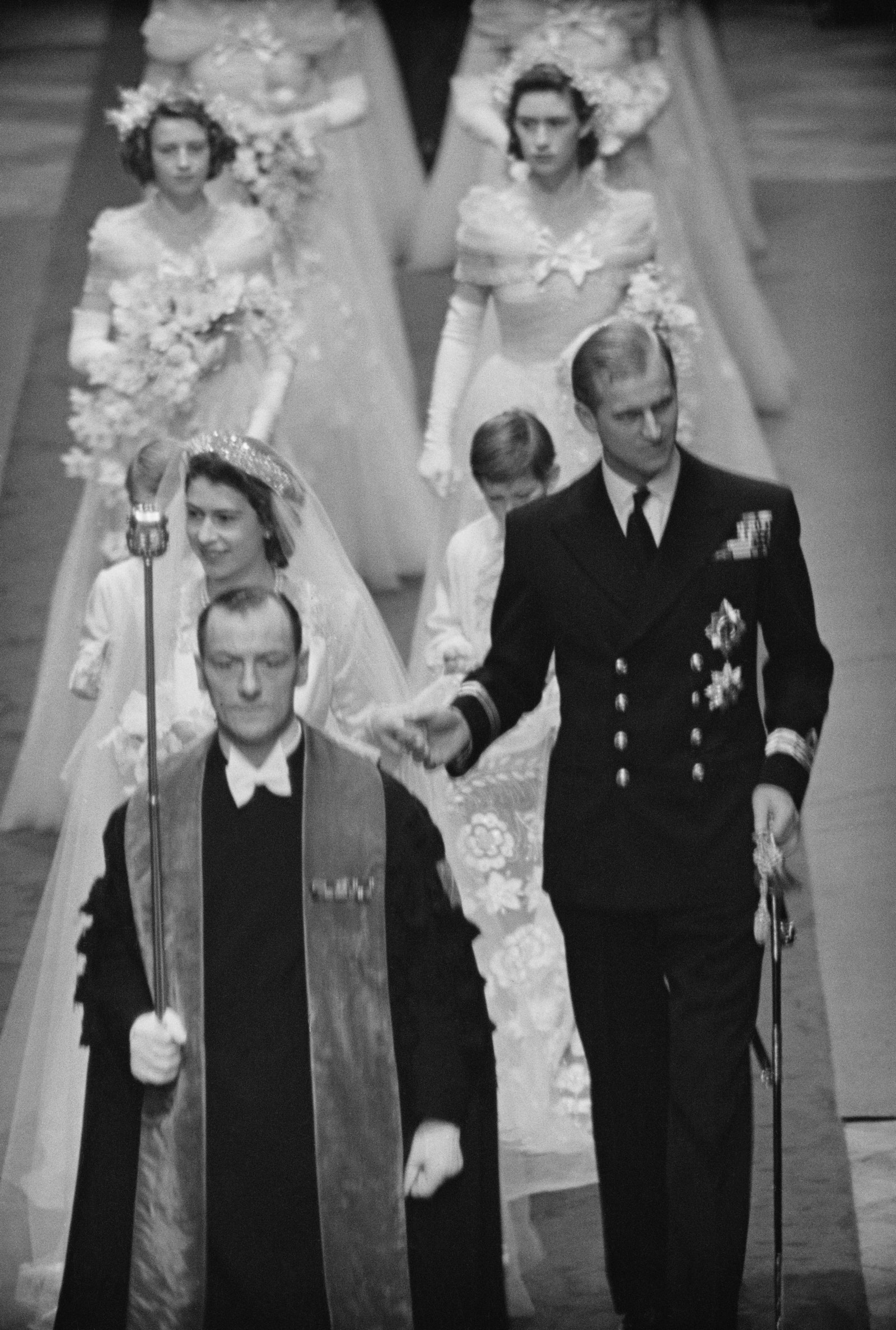 Princess Elizabeth making her way down the aisle with the Duke of Edinburgh, followed by bridesmaids in flower crowns.