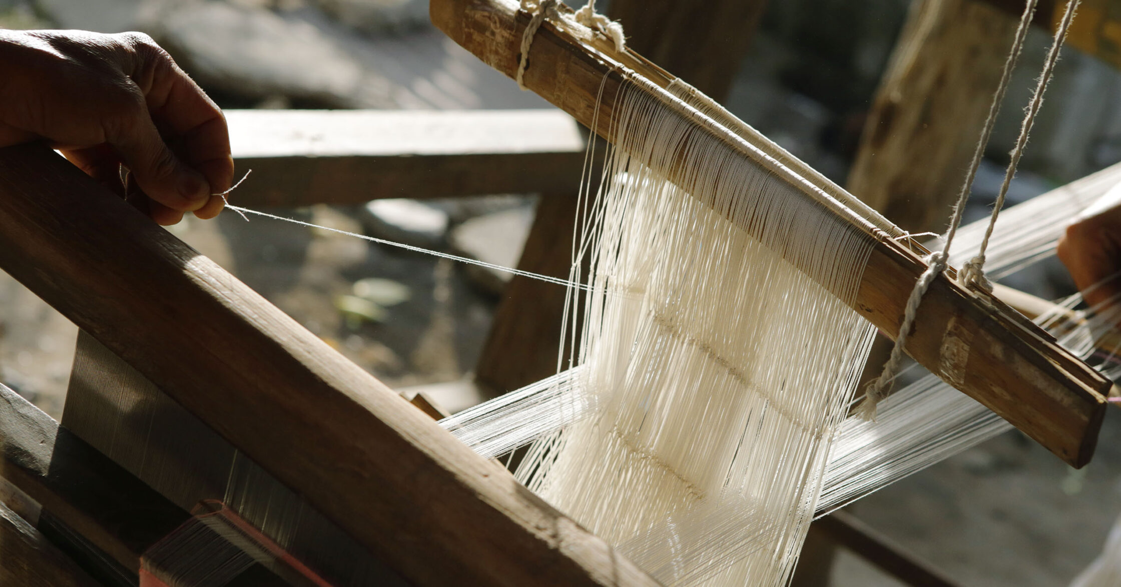 A weaver setting up a traditional floor loom