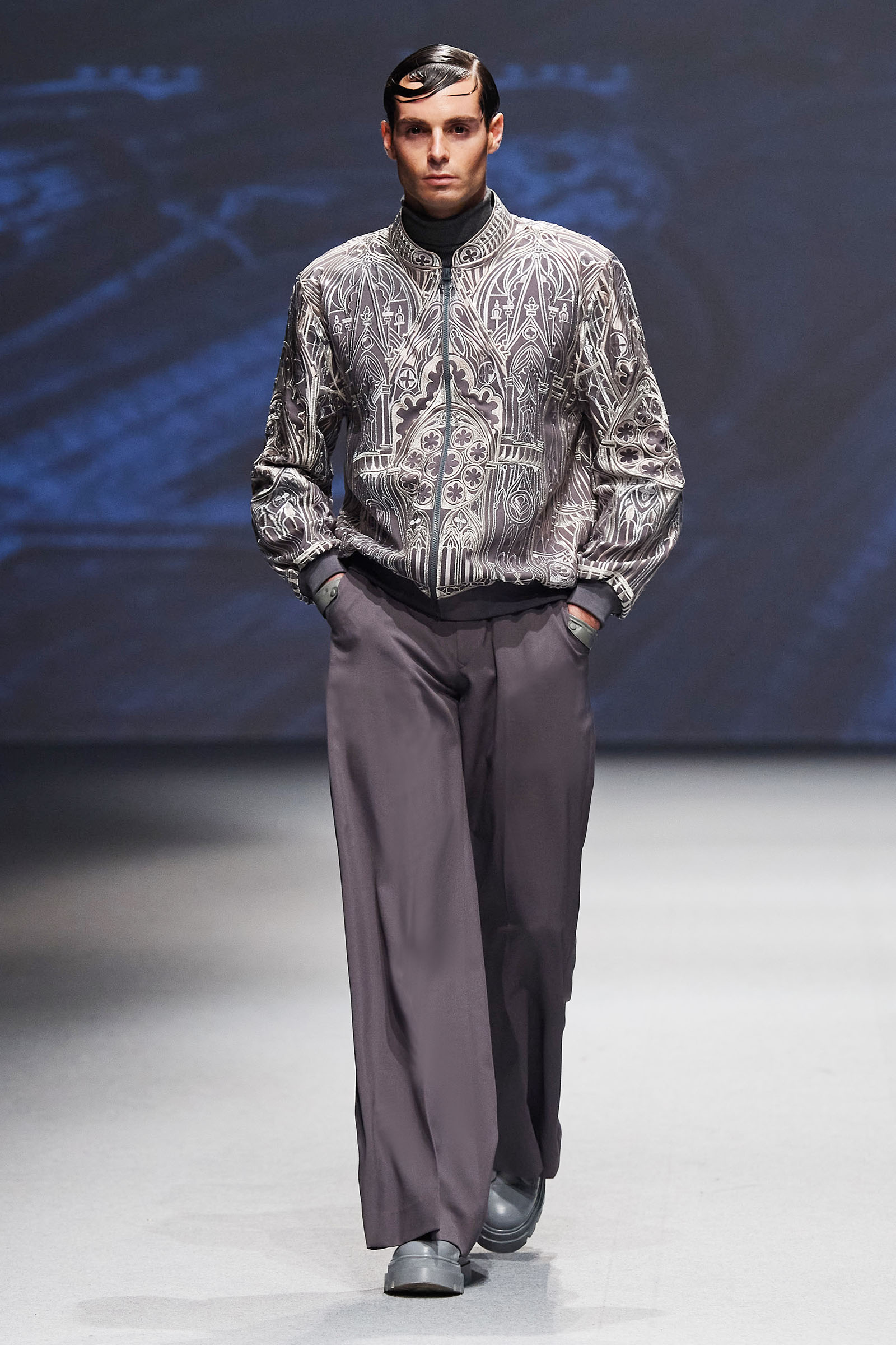 Michael Cinco runway look silver jacket intricate design with gray slacks