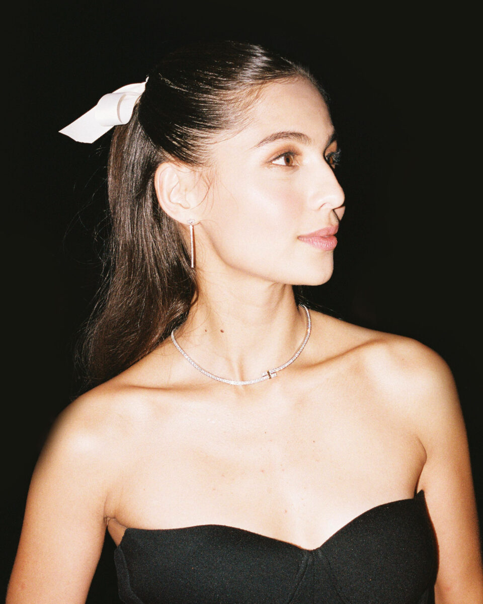 Jasmine Curtis-Smith wearing a half up-do hair with white ribbon and black dress