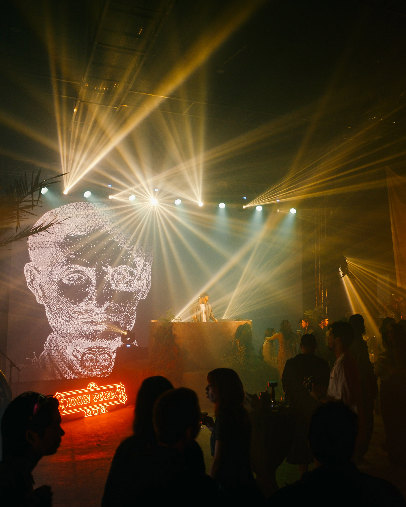 A DJ playing music for guests of Don Papa Rum set against a light show and Papa Isio's image
