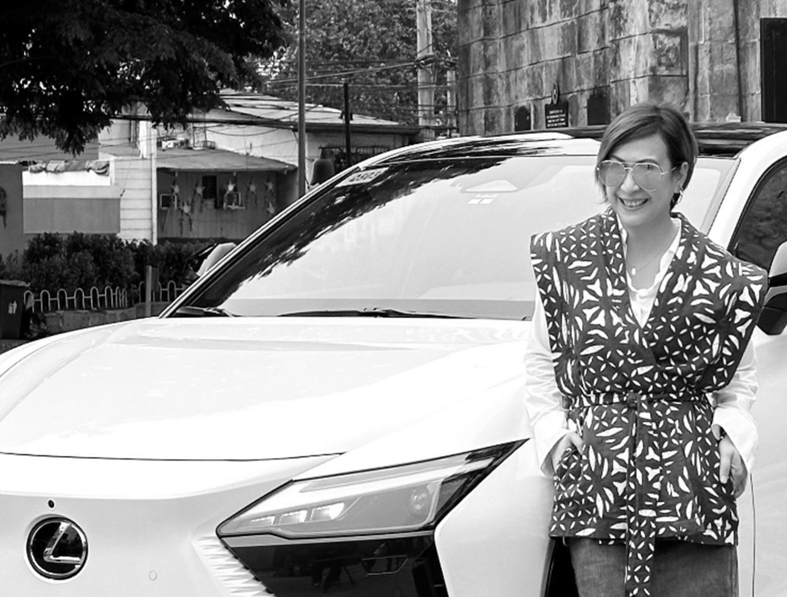 Kitty Bunag posing beside the Lexus RZ in black and white
