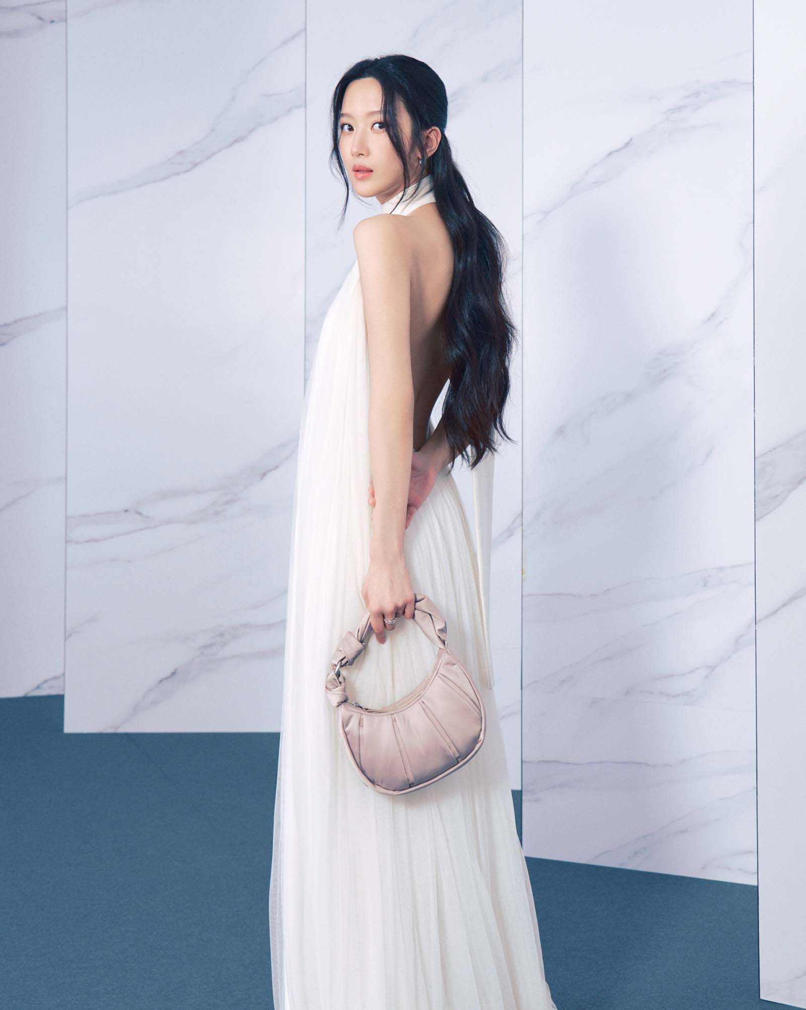 Mun Ka-Young wearing a white backless dress and the TUMI Asra crossbody in Moonlight